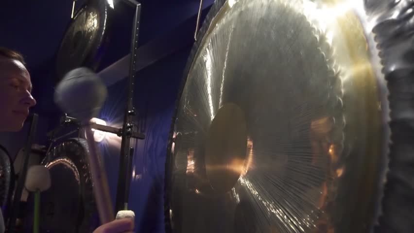 Woman is playing big gongs during healing yoga gong practice. Sound therapy. Mindfulness, tranquility and harmony.