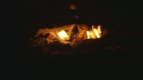 A close up shot of wood embers burning in a stove during night