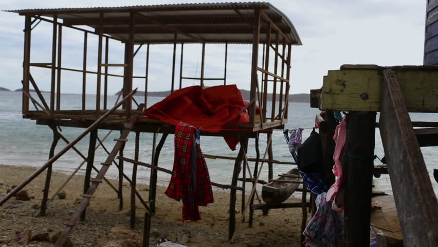 A side angle view of open sea from beach with an under construction wooden cottage in between