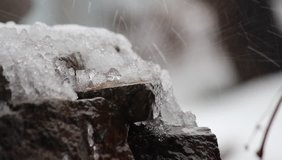 Melting snow on natural stones. Waterfall, ice, water. Hello Spring. Selective focus.