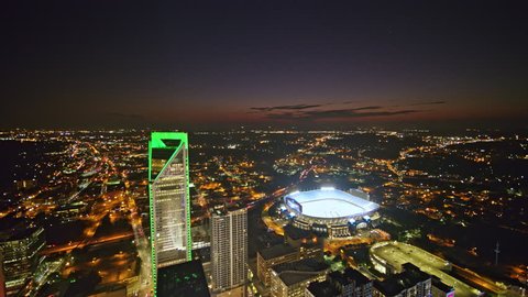 North Carolina Charlotte Aerial Flying through downtown cityscape at dusk in reverse away from stadium 10/17