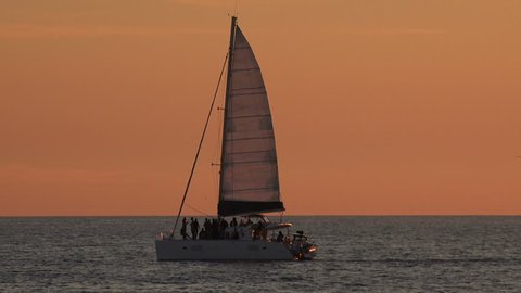 A sailboat in the ocean at sunset

