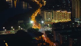 Night city crossroad aerial view, road traffics and neon lighted skyscrappers blinking buildings, view video China, Hainan, Sanya