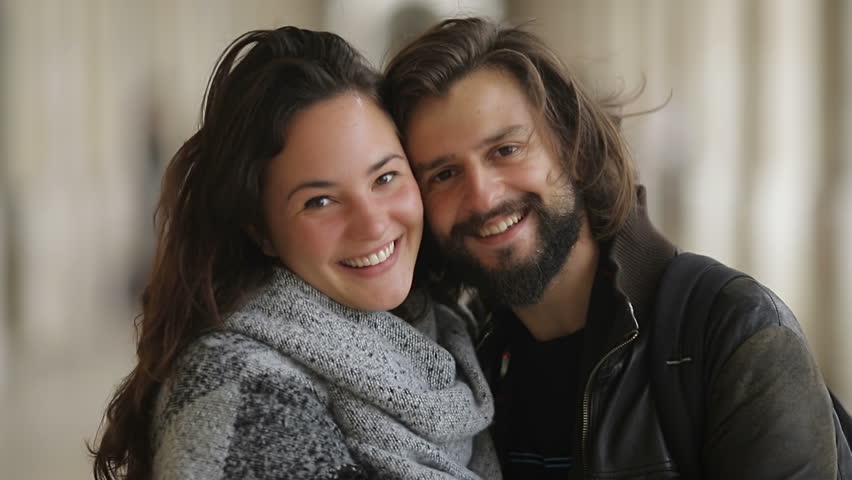 Bearded young man kissing his girlfriend. Happy couple in love hugging and looking at camera. Hapiness concept
