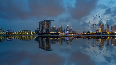 Beautiful Time lapse of Day to Night of Singapore skyline from afar with reflection. Prores. Pan right motion timelapse. 4K available.