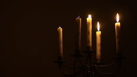 Candlestick with five candles in the darkness. Only light in the room.
