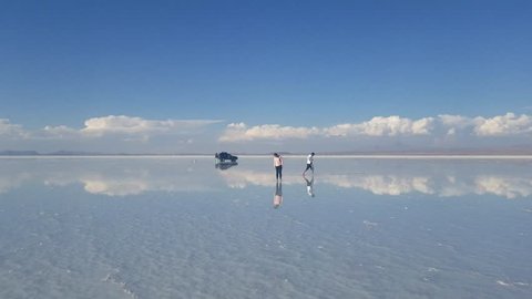 Salar de Uyuni arid Salt flats. People walking and a 4x4 Extreme Terrain vehicle ready for adventure