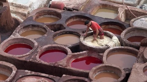 FEZ, MOROCCO - CIRCA FEB 2018: Men working as a tanner in old tanks at leather tanneries with color paint. Ancient medina, Chouara Tannery, Fes el Bali