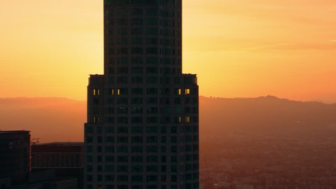 Soaring near high rise buildings around downtown Los Angeles at sunset. Aerial wide shot filmed with a RED camera.