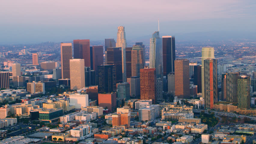 Aerial helicopter shot flying around downtown Los Angeles at sunset. Wide shot filmed with a RED camera.
