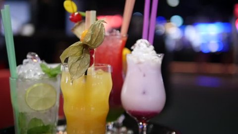 Close up of colorful drinks. Several various cocktails and colorful drinks in a nightclub or pub on a blurred background with lights