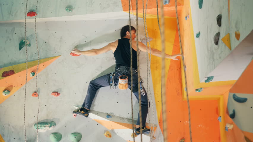 One man hold rocks while climbing on a wall, close up.