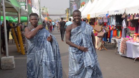 Accra, Ghana - December 21, 2018: Ghanaian men dress up in traditional African fabrics on a street.