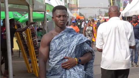 Accra, Ghana - December 21, 2018: Ghanaian man dress up in traditional African fabrics on a street.