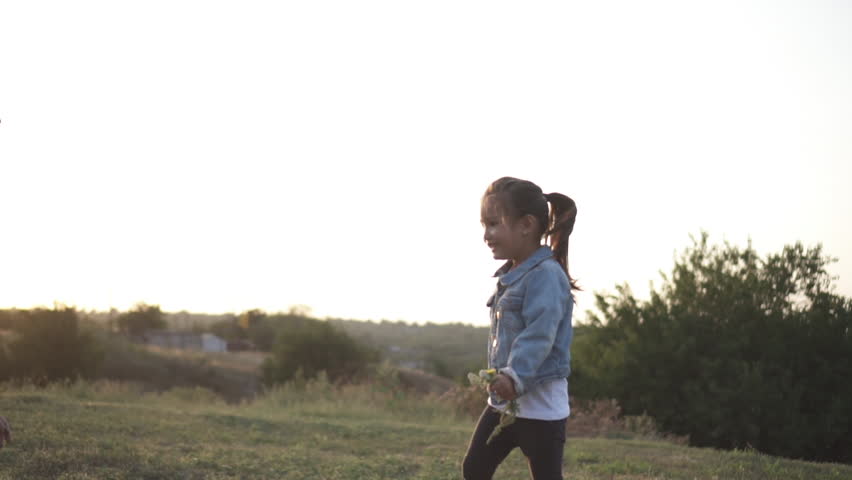 Little chinese girl runs around and try to catch her mother in park. Mixed race family, european mother and asian doughter, spending time in the park on sunset. Warm spring or summer season. Close up