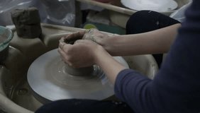 A close up video clip of hands working with clay on a pottery wheel.
