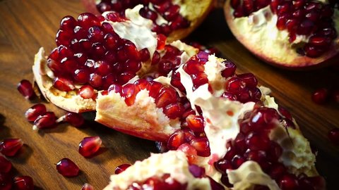 Pomegranate fruit is broken into pieces. Pomegranate seeds lie on a platter. Juicy red fruit on a cutting board. Beautiful pomegranate pulp.