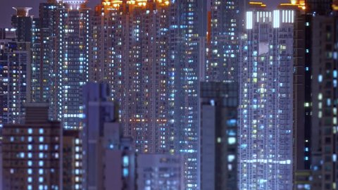 Loop of Hong Kong apartments at night. Chinese crowded city with lights turning on and off at midnight. Fast paced modern Asian night-scape time lapse in urban metropolis.