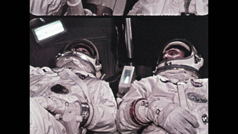 1960s: Astronauts inside spaceship. Crane moves surface module craft.