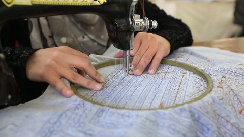 Arab woman embroidering a dress In a sewing workshop.