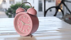 Pink alarm clock on wooden board. Tracking shot.