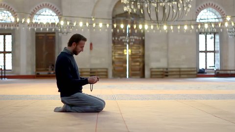 Muslim young male with rosary beads praying in mosque