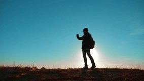 Male man worth it tourist with backpack smartphone navigation sunlight stands on top of a mountain. slow motion video. man silhouette at sunset. hikers adventure and the go walking lifestyle. 