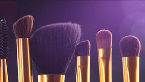 Make-up Brushes set over black holiday blinking background. Various Professional makeup brush on dark backdrop in studio. Make up artist tools. Dolly shot. Slow motion. 4K UHD video