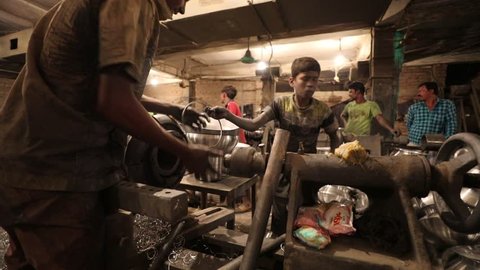 DHAKA, BANGLADESH - DECEMBER 07, 2018: A young childlabour worker is working in a sweatshop in Bangladesh producing metal or aluminium pots under dangerous circumstances