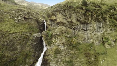 Amazing aerial shot of a waterfall in the middle of mountains. Beautiful natural landscape. Camera moving forward and then up for a great mountain view. Spain. 60 fps. HD 
