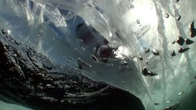Underwater video shooting under ice in cold water of people on ice surface as concept of winter wild nature of lake Baikal.