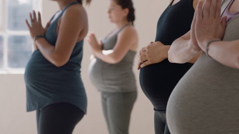 yoga class portrait pregnant caucasian woman practicing warrior pose with instructor teaching posture group of women enjoying healthy lifestyle exercising in fitness studio