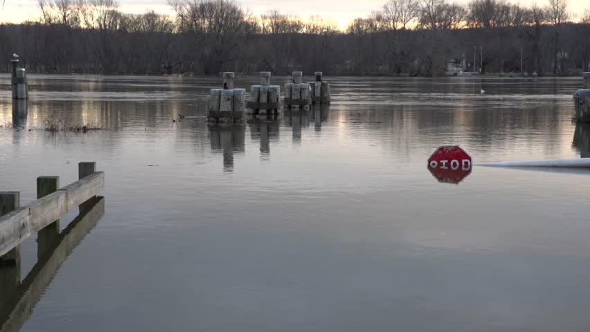 Static Clip of the Connecticut River in Rocky Hill flooded over the roadway ramp to the ferry. Water is rushing down the river almost covering the stop sign and roadway.
