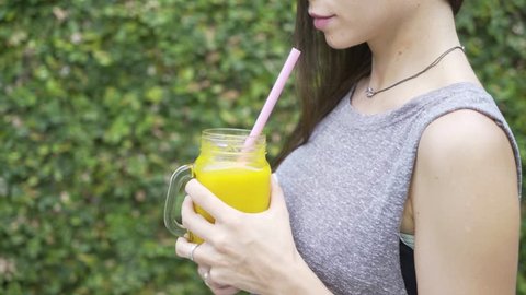 A young fit girl drinking mango smoothie. Healthy organic drink. Fitness vegan lifestyle