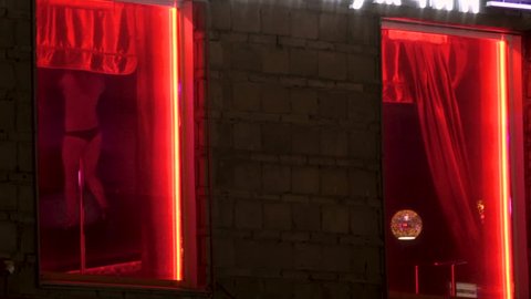Surveillance room privat with red neon. Women dance strip for men. Girl undress near the window. Dance of women without clothes on street of Amsterdam red light district. Light erotica in nightclub 4k