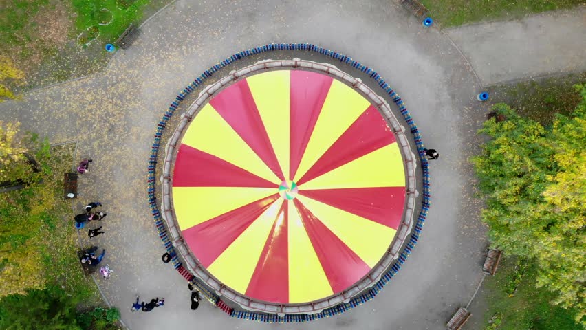 CHERKASY, UKRAINE, OCTOBER 17, 2018: Colourful, red and yellow carousel, a carnival Merry Go Round, in the autumn park, aero, view from above.