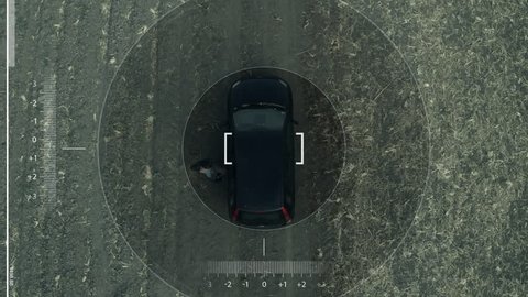 Aerial view of black car on dirt road through countryside, top view of vehicle, animated HUD mock up as seen from police surveillance drone pov