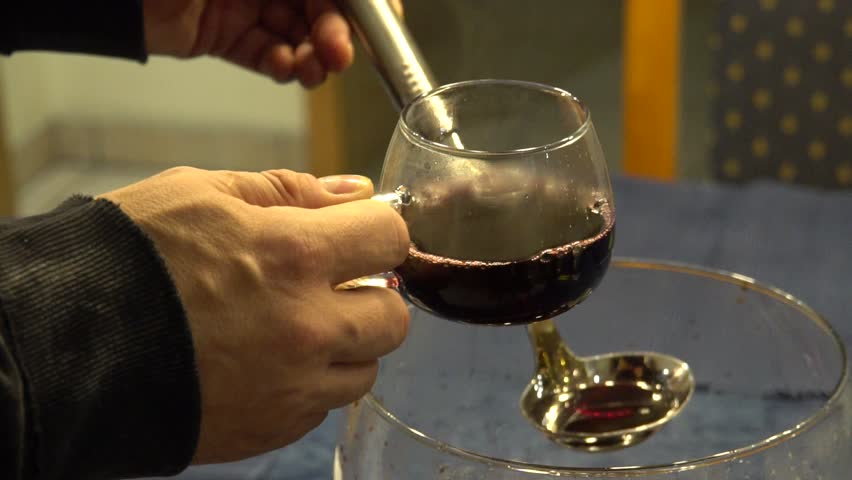 Preparation of hot mulled wine. Pouring Fire Tongs Punch Into The Glass. A popular warm alcoholic drink to entertain. Slow Motion And Close Up.