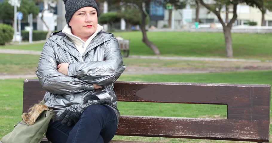 Middle aged woman in depression sitting on a park bench
