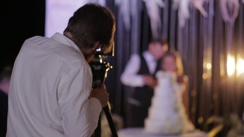 Image of movie shooting or photographing on Wedding day. Video production with camera equipment at indoor location. Loving wedding couple the bride and groom on the background, blur place for text