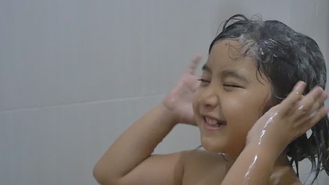 Happy Asian child washes hair in bathroom, Slow motion shot