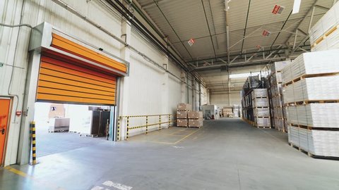 VINNITSA, UKRAINE - MAY 2018: Orange rolling door of the warehouse is closing. Rolettes work with the help of automation. Motion of rolling door to down