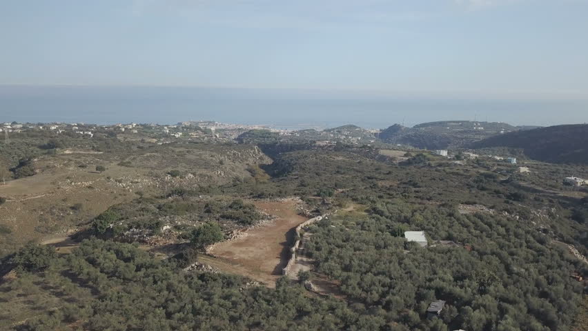 Mediterranean landscape with green hill with olive trees. Blue sea on the skyline. Greece, Crete
