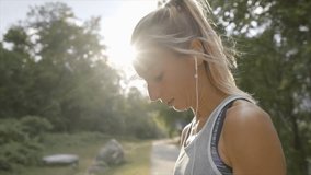 Young woman jogging outdoors using mobile phone app choosing music for morning training in forest path. People healthy lifestyle concept - Slow motion 