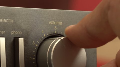 Turning up the volume up to the maximum, closeup of a hand turning the volume dial on a vintage stereo