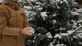 Young man is making and then throwing a snowball in winter, medium shot