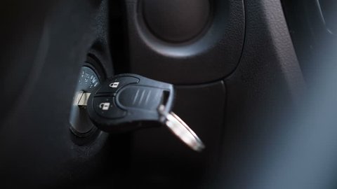 Close-up. Female hand turns off the car. Keys, ignition