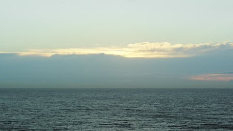 Static wide shot of calm ocean at sunrise/sunset