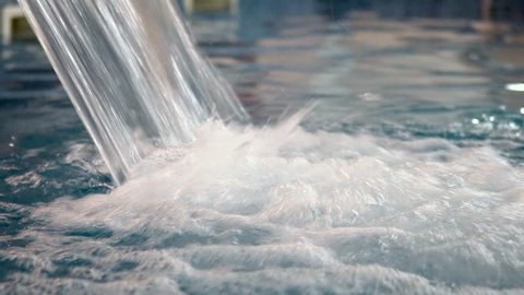 Water splashing into the pool from waterfall jet, water jet for hydrotherapy 