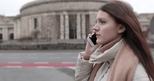 Busy girl walking on the street and talk on her phone with buildings background around her. 4K Footage - Video
